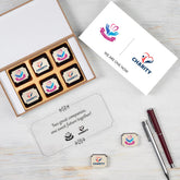 Open MDF wooden box filled with logo‑printed chocolates for merger announcement