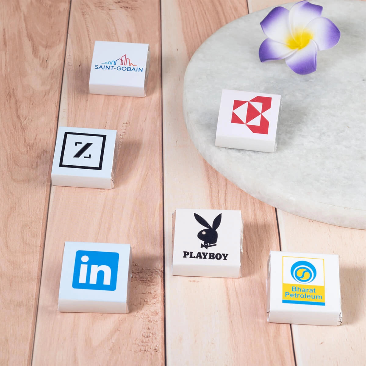 Close-up of individually wrapped dark chocolates featuring company logos.