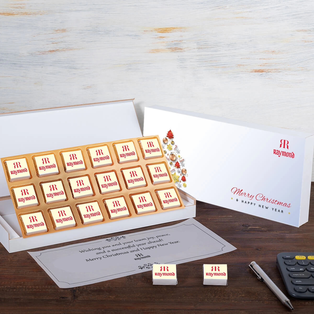 Open white wooden gift box displaying 18 custom-branded chocolates with a personalized butter paper message.