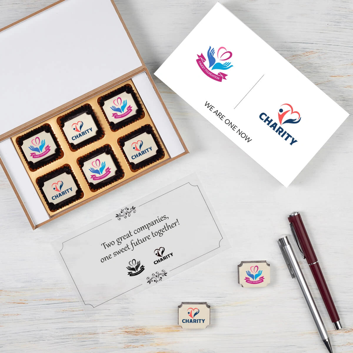 Open MDF wooden box filled with logo‑printed chocolates for merger announcement
