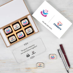 Open MDF wooden box filled with logo‑printed chocolates for merger announcement