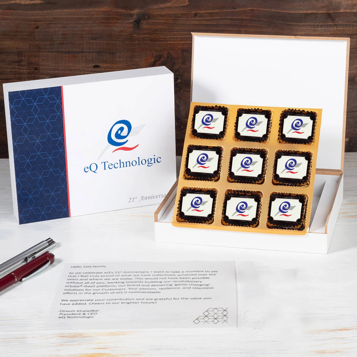 Open wooden box with 9 logo chocolates and personalized butter‑paper message – company anniversary gifts