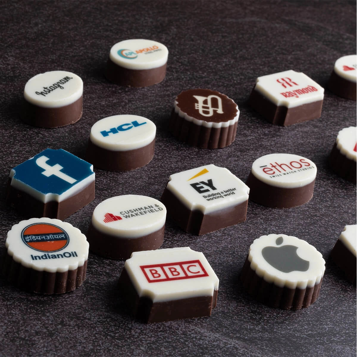 Logo chocolate close-up: white‑chocolate top with dark‑chocolate base and crisp corporate logo